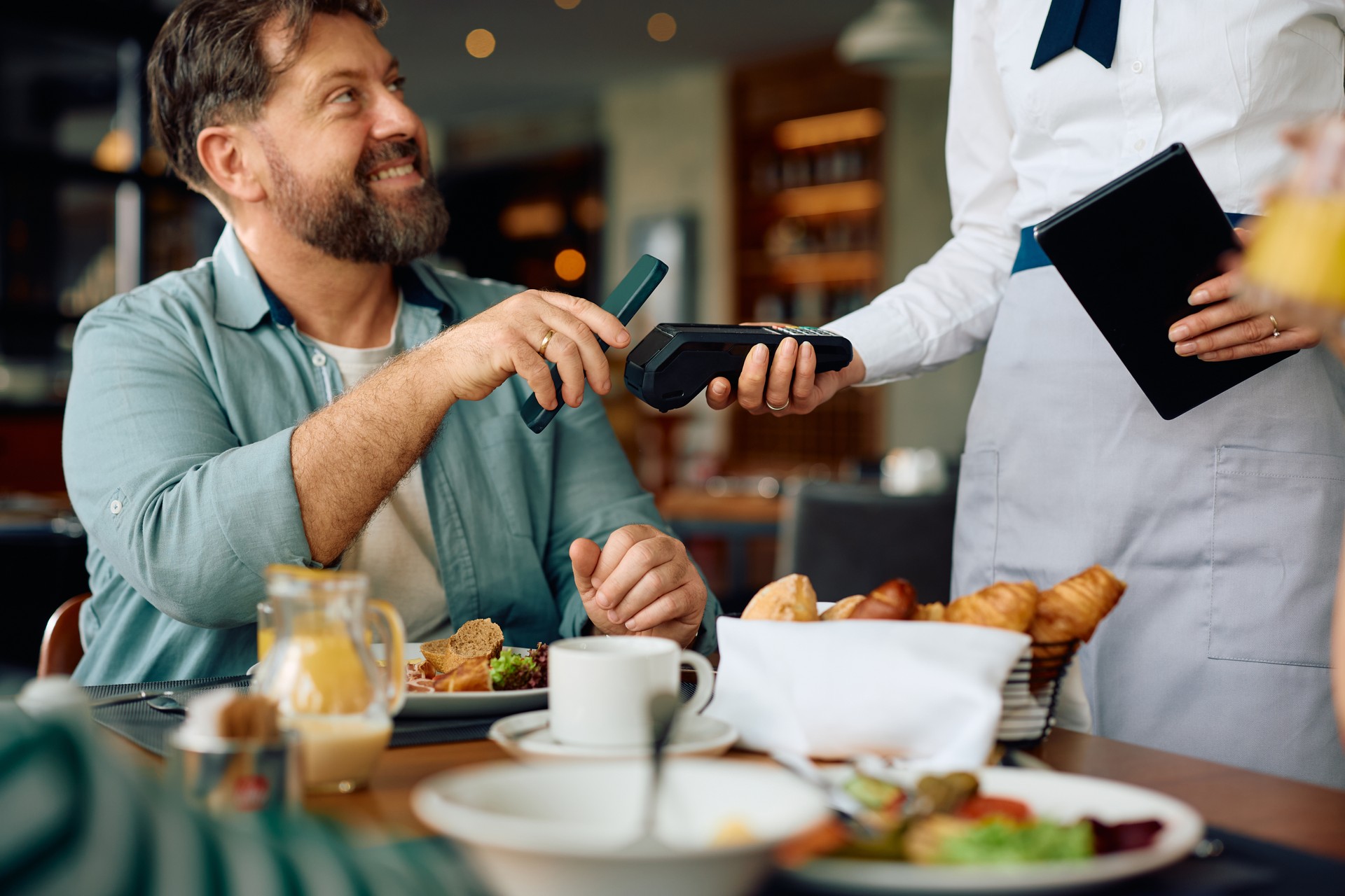 Close up of man paying contactless after having a breakfast in restaurant. Close up of man paying contactless after having a breakfast in restaurant.